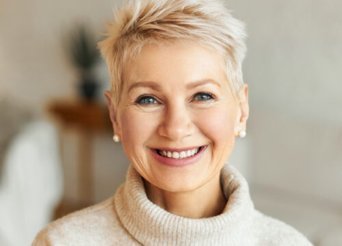 Photo of an elegant older woman smiling, wearing a turtleneck sweater