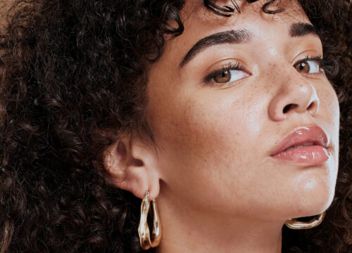Woman with great skin and curly hair wearing gold earrings