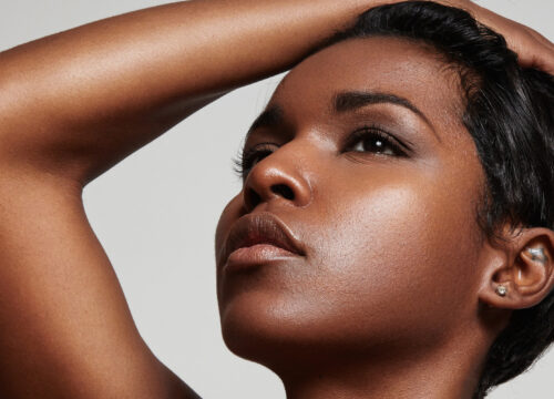 Photo of an African American woman with short hair putting her hand on her head